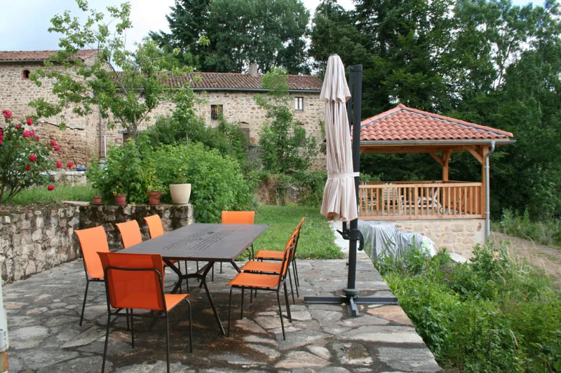 Terrasse dallée avec table orange, parasol et gazebo en bois au fond