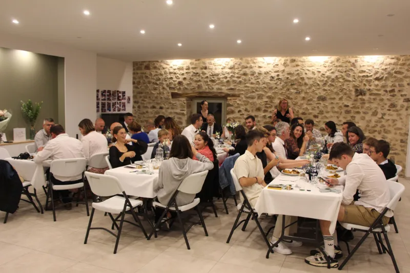 Salle de repas en pierre avec tables dressées et groupe en fête