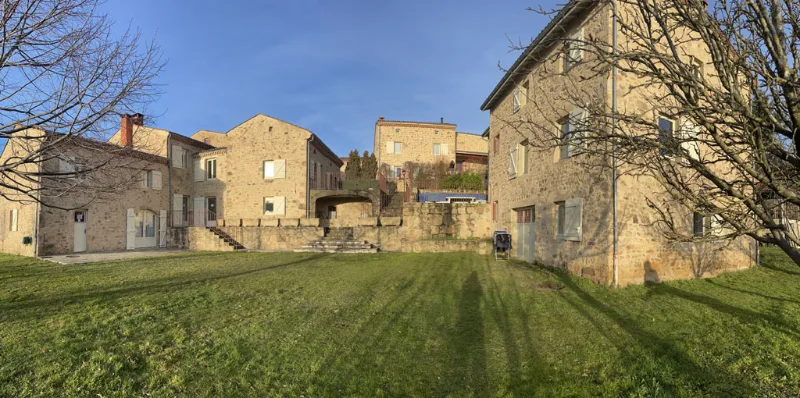 Hameau en pierre avec grande pelouse et ciel dégagé au coucher de soleil