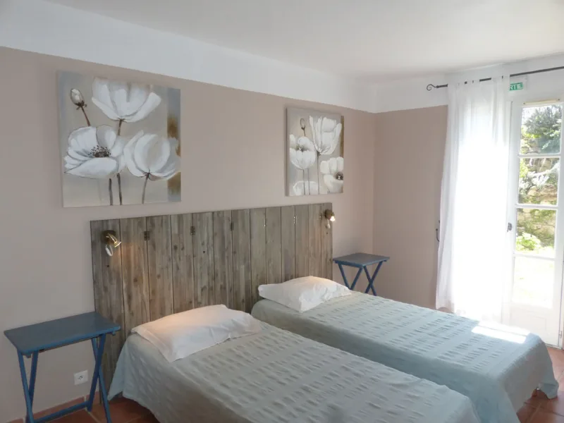 Chambre twin épurée avec tête de lit bois flotté et tableaux floraux