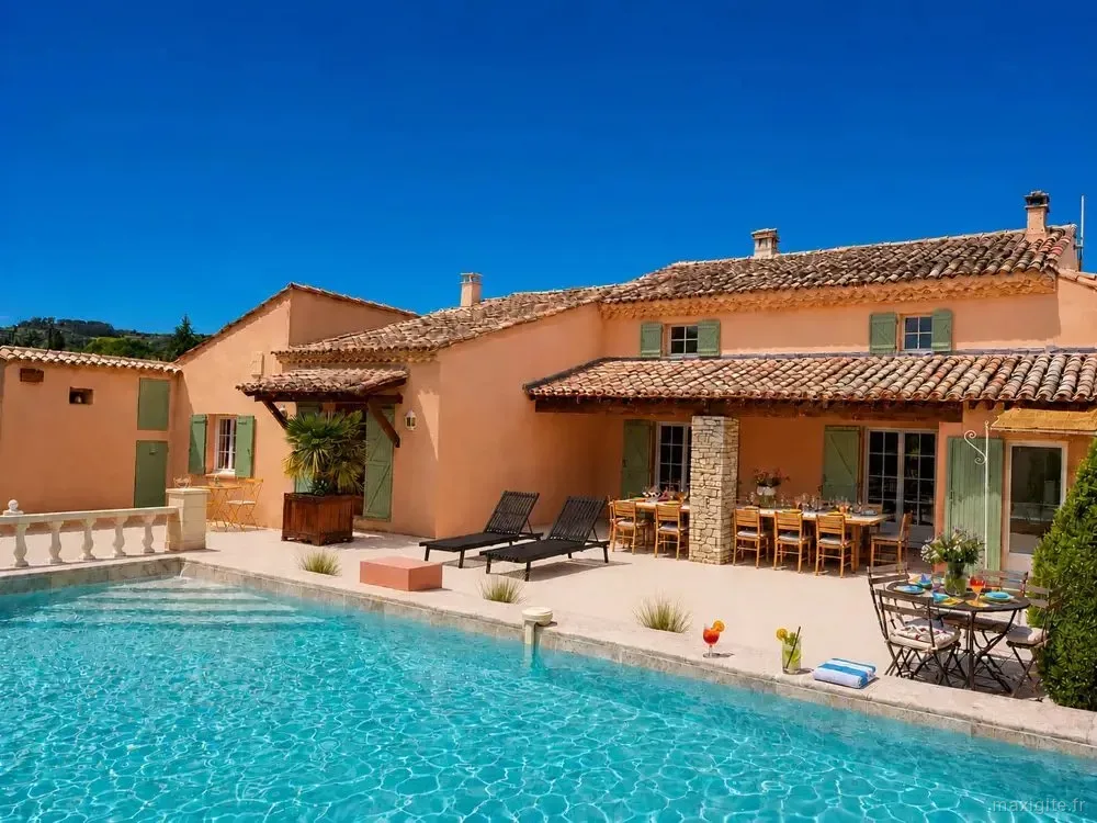 Gîte de groupe Le Mas Séquana à Roaix — Façade ocre du mas aux volets verts avec terrasse, table dressée et piscine turquoise au soleil, capacité 18 personnes