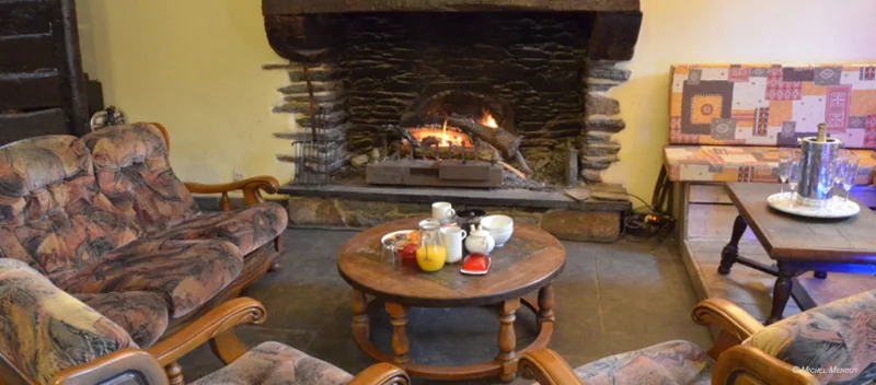 Salon chaleureux avec canapés à fleurs autour d'une table basse et feu allumé dans la cheminée