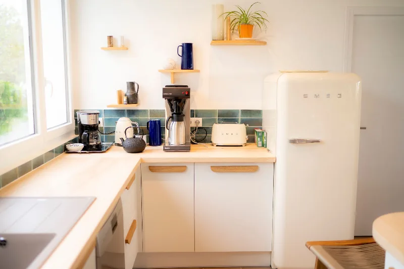 Cuisine équipée avec frigo et grille-pain SMEG crème, plan de travail bois et crédence en faïence verte