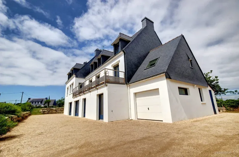 Facade de la maison aux toits d'ardoise avec balcon, garage et large cour gravillonnee