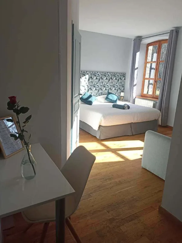 Chambre lumineuse avec lit double, coin bureau, parquet et grande fenetre a meneaux