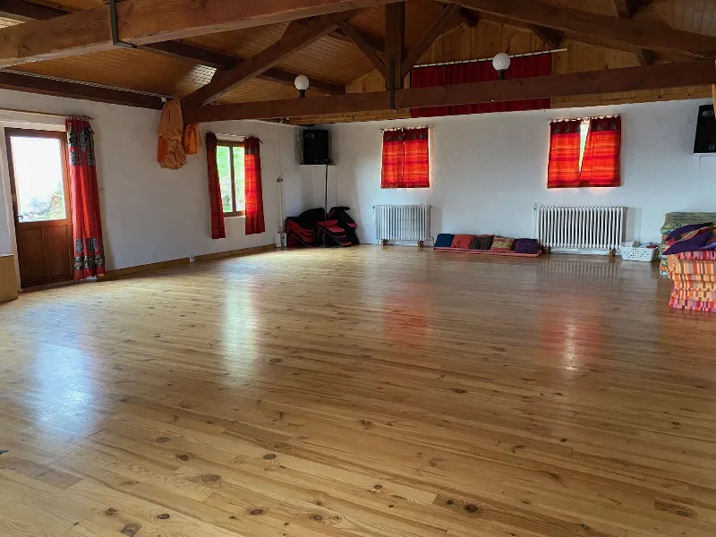 Vaste salle commune au parquet clair sous charpente bois, ideale pour activites de groupe
