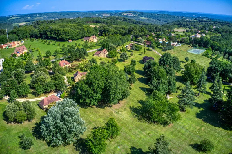 Vue aérienne du domaine niché dans la campagne vallonnée et boisée à perte de vue