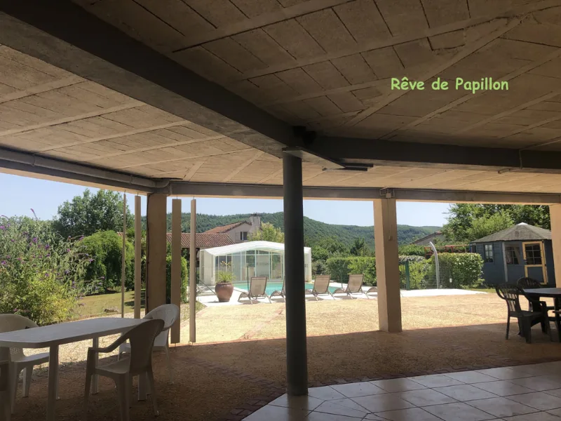 Terrasse couverte spacieuse donnant sur la piscine, le jardin et les collines en arrière-plan
