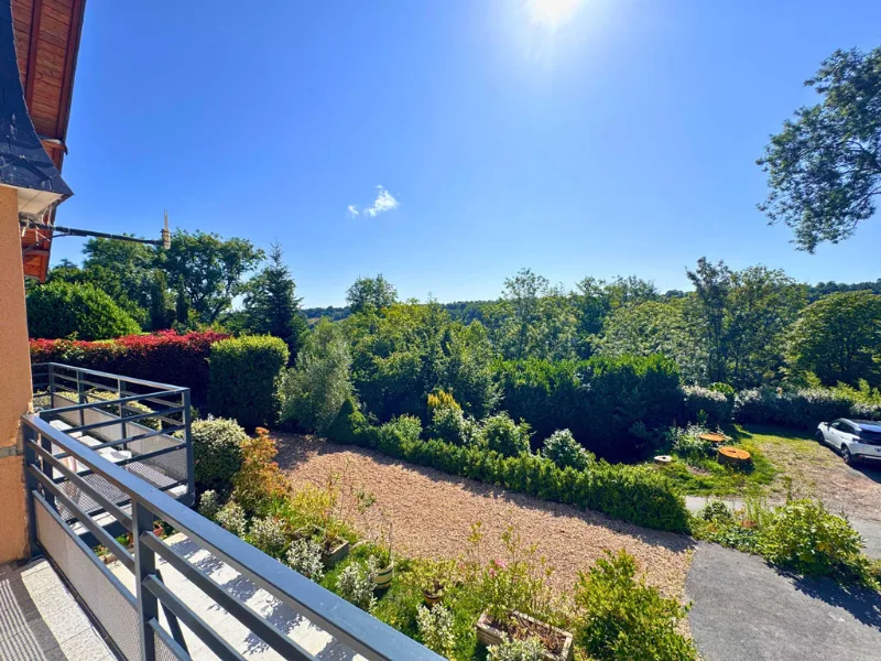 Vue depuis balcon sur jardin verdoyant et ciel bleu ensoleillé