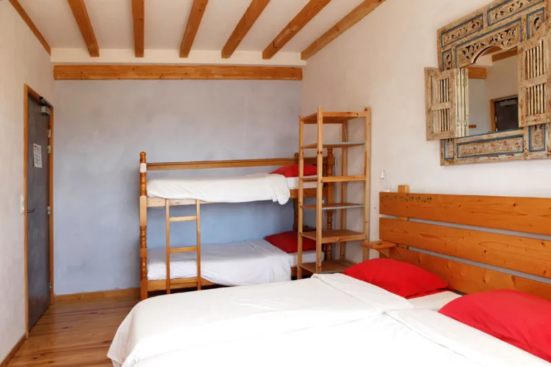 Chambre avec lit double, lits superposés en bois et miroir sculpté, poutres apparentes