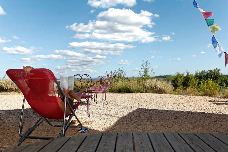 Terrasse gravillonnée avec transat rouge et panorama dégagé sur la campagne environnante