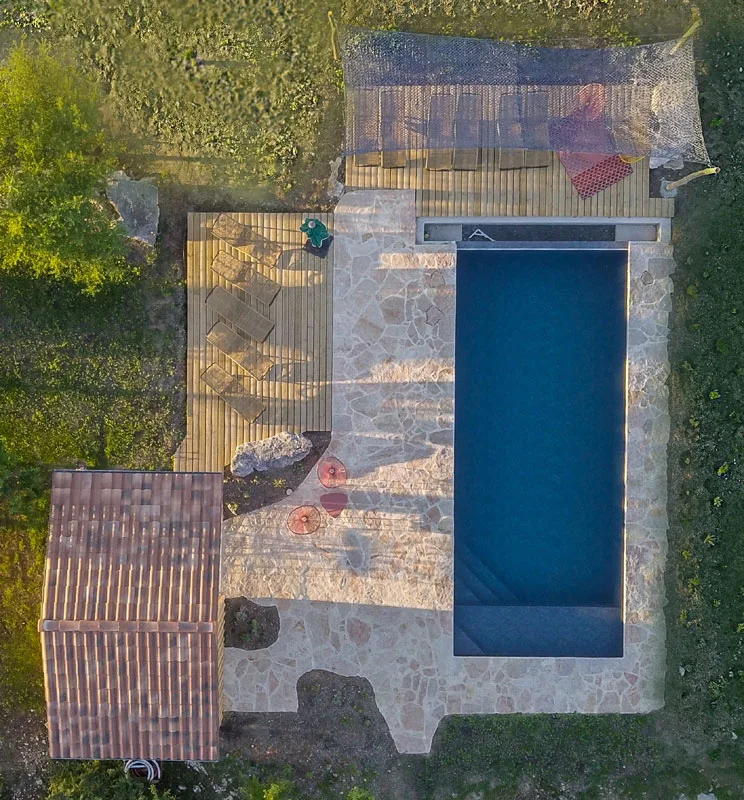 Vue aérienne de la piscine rectangulaire et de sa plage pavée bordée d'un petit bâtiment