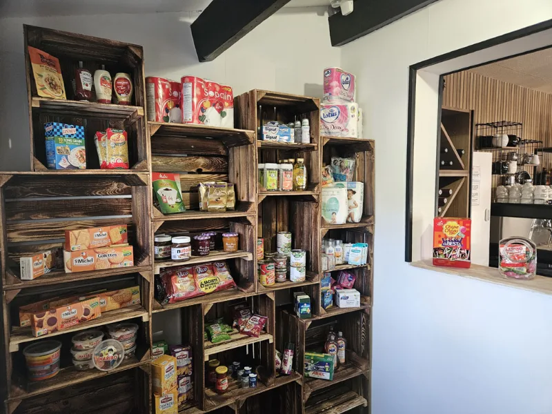 Petit coin épicerie avec étagères en caisses de bois garnies de produits et boissons