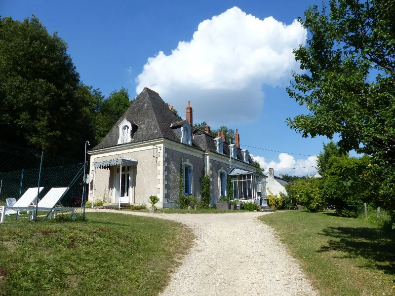 Allée de gravier menant à un manoir en pierre avec grandes pelouses