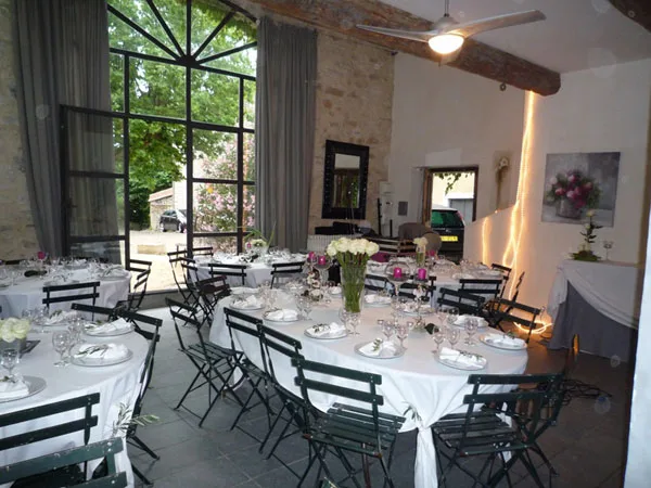 Salle de réception aux tables dressées sous grande verrière, idéale pour banquets nombreux