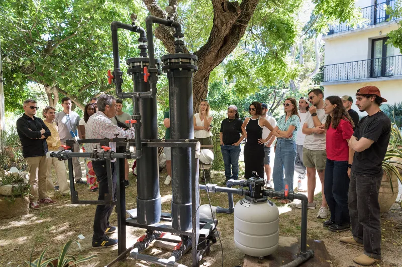 Groupe rassemblé dans le jardin autour d'une installation technique pour une démonstration explicative