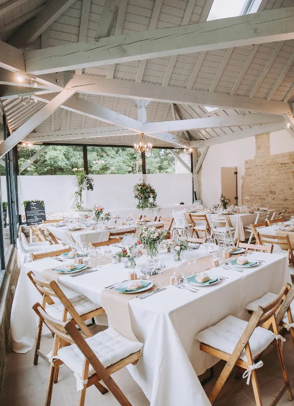 Grande salle de réception du domaine avec tables dressées pour une fête, décorées de fleurs, sur 72 m²