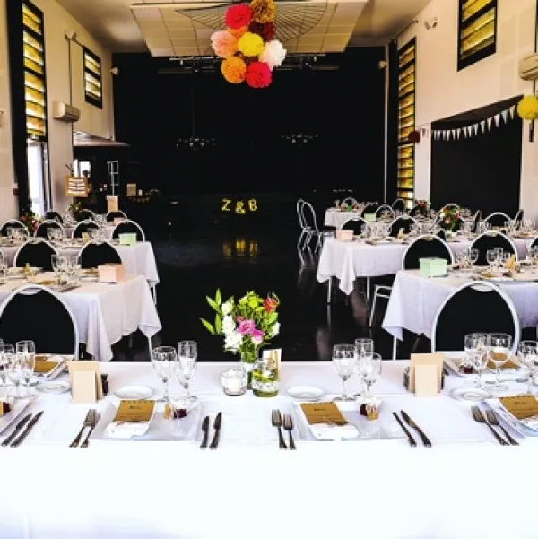 Salle de réception dressée pour mariage avec pompons colorés au plafond