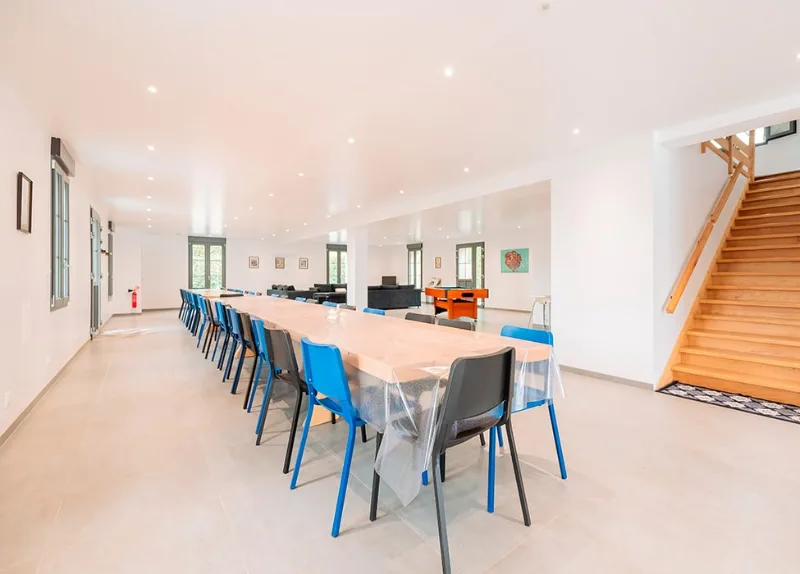Grande salle à manger lumineuse de 200 m² avec longue table et salon, pièce à vivre principale du gîte