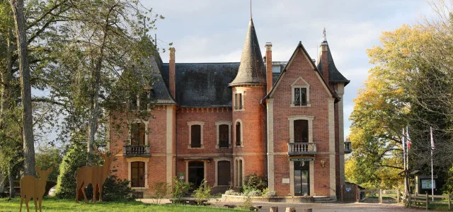 Gîte de groupe Maison du Garde et la Grange – Domaine du Ciran à Ménestreau-en-Villette — Château en brique rouge avec tourelle et sculptures de cerfs en métal, capacité 23 personnes