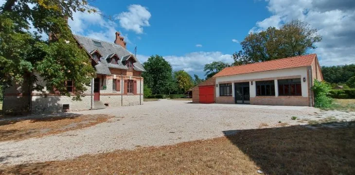 Maison du garde en pierre et grange à toit orangé sur cour en gravier