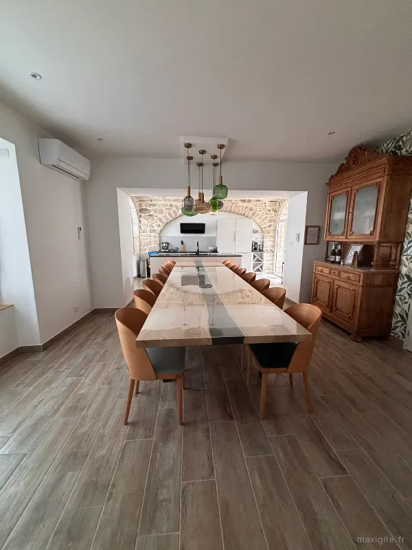 Grande salle à manger avec table rivière en sycomore de 4,70 m et cuisine ouverte sous arche en pierre de taille