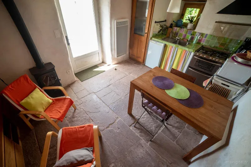 Espace cuisine d'été couvert avec plancha, table et murs en pierre volcanique