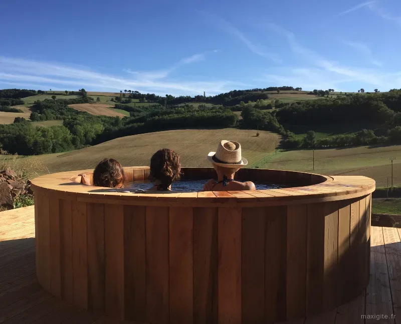 Sauna-tonneau en bois sur terrasse avec vue panoramique sur les collines aveyronnaises