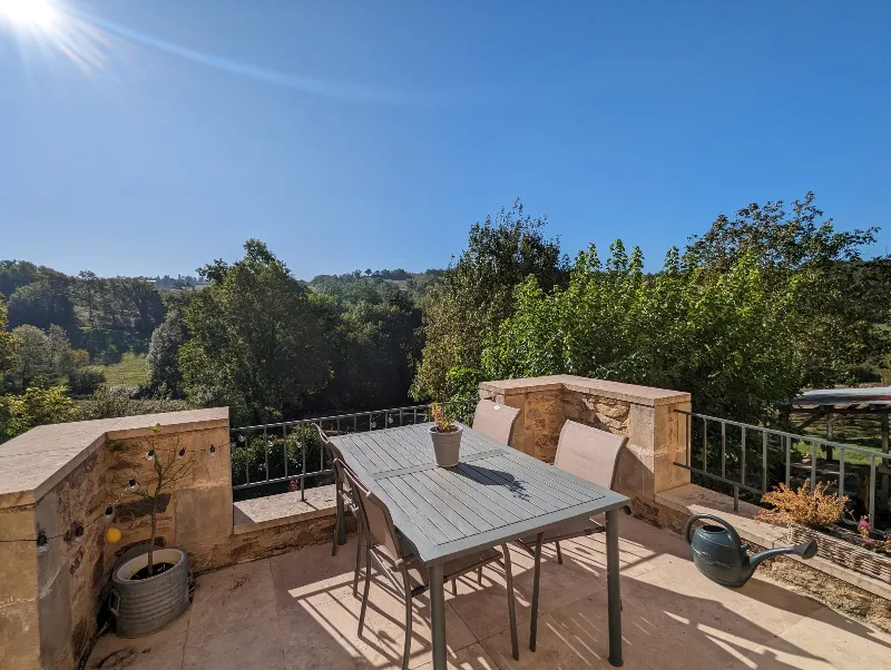 Terrasse de la suite avec table et chaises, vue panoramique sur les collines verdoyantes d'Occitanie