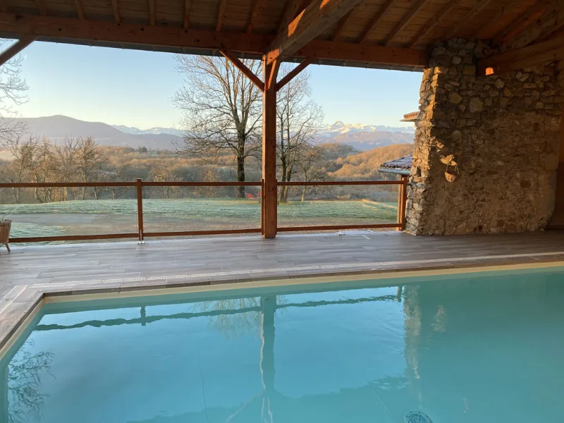 Piscine couverte sous charpente bois avec vue panoramique sur montagne