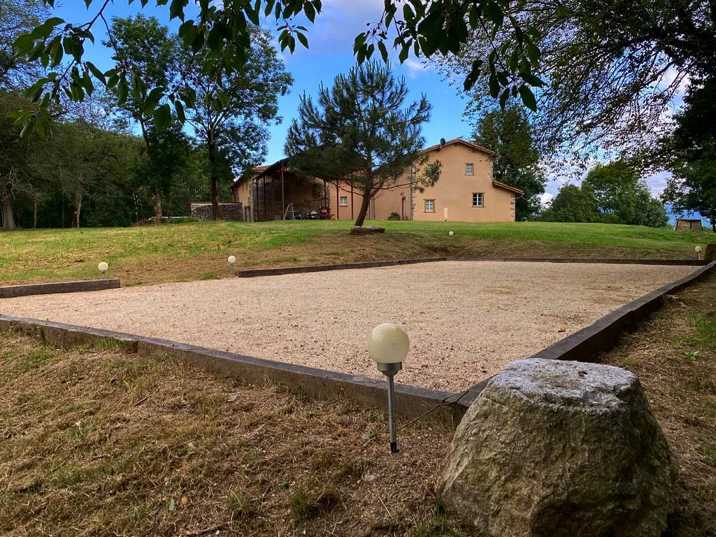 Gîte de groupe Gîte de Caville à Montesquieu-Avantès — Terrain de pétanque en gravier avec boulodrome et bâtisse en fond, capacité 15 personnes