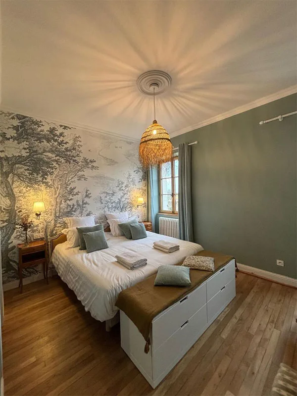 Chambre avec papier peint toile de Jouy grise, suspension raphia et coussins verts