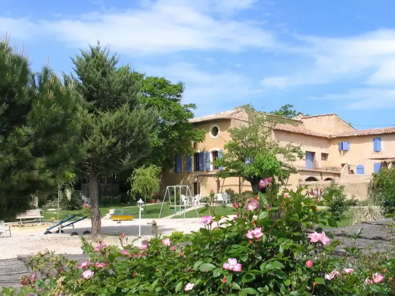 Façade et extérieurs de la Bastide de la Peyrolière avec jardins méditerranéens et pins sous le soleil du Luberon