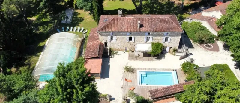 Vue aérienne de La Buissière avec ses deux gîtes, le parc arboré de 8 400 m² et les piscines dans le Lot