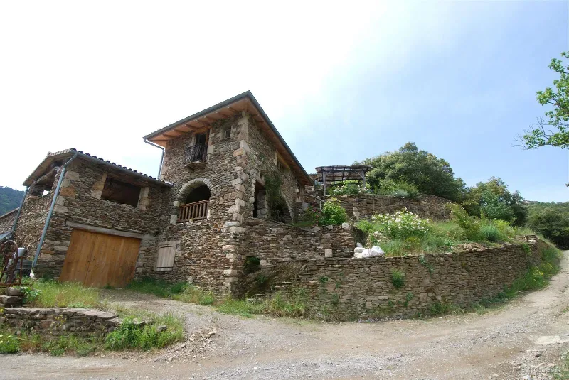 Hameau en pierre sèche avec grange en bois sur chemin de terre en montagne