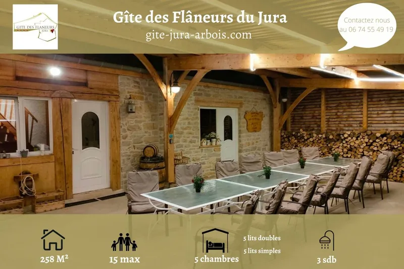 Salle de réception  du gîte jurassien illuminée le soir, vue sur les vignes et le village d'Arbois