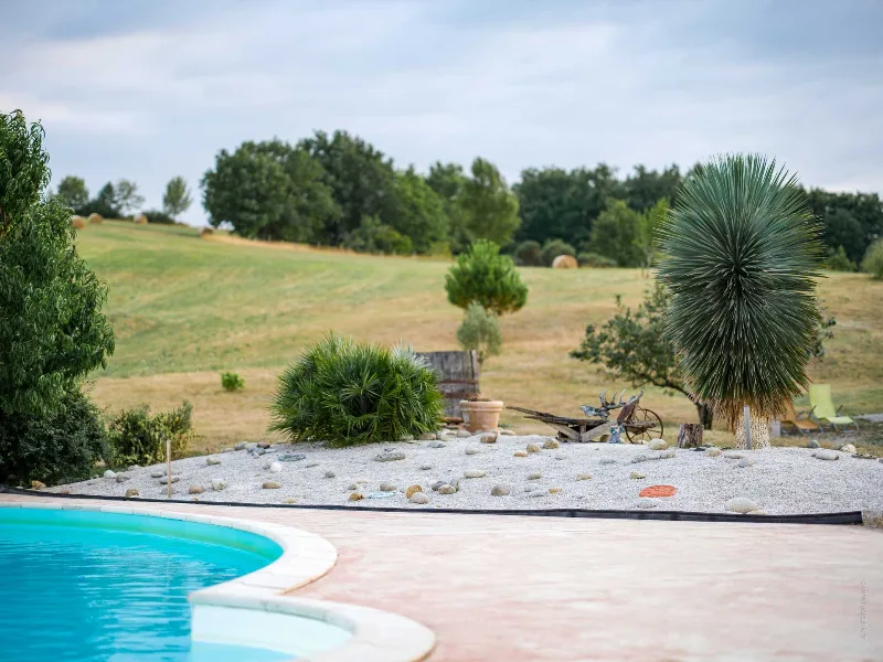 Bord de piscine avec jardin de rocaille, yucca et prairie aux balles de foin