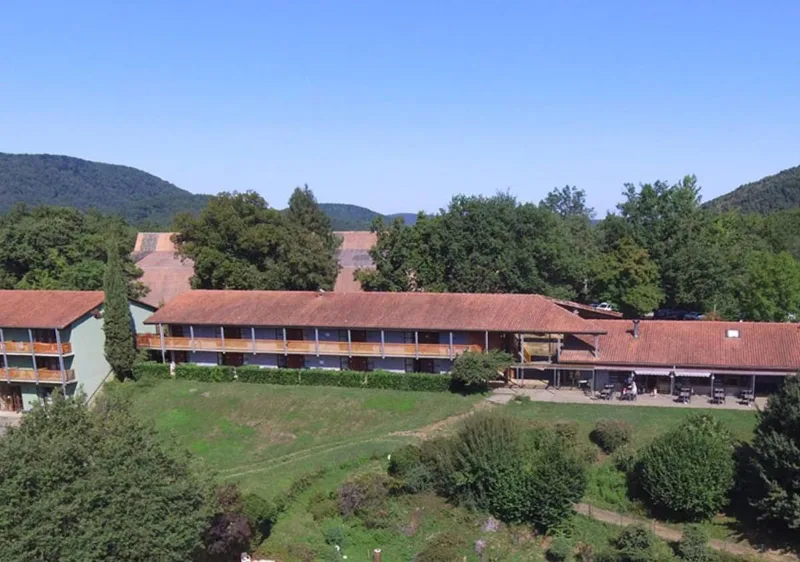 Vue aérienne d'un long bâtiment avec balcons en bois et toit rouge en montagne