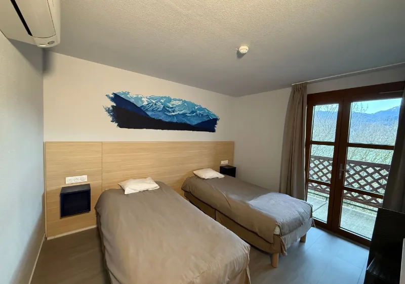 Chambre twin moderne avec fresque montagne au mur et balcon sur massif pyrénéen