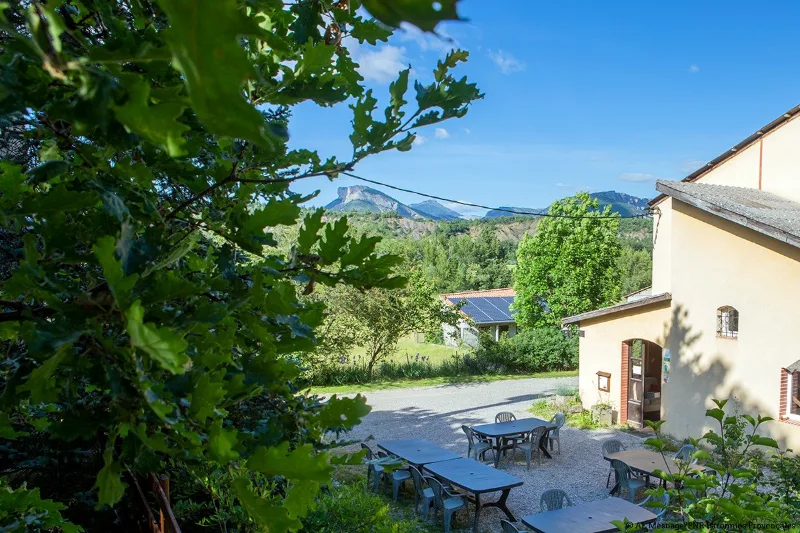 Terrasse extérieure avec tables de pique-nique et vue dégagée sur les collines de la vallée du Buëch