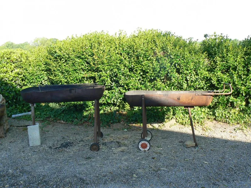 Deux broches de barbecue artisanales en métal rouillé sur cour en gravier