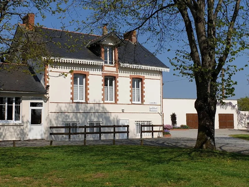 Maison bourgeoise blanche avec pelouse et tables de pique-nique sous grands arbres