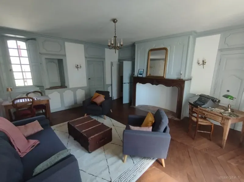 Salon lambrissé avec cheminée en pierre, fauteuils et bureau ancien, espace de détente élégant