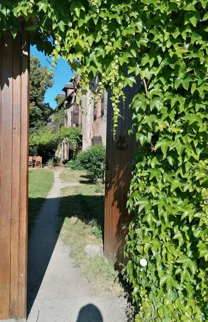 Gîte de groupe L'Arche d'Yvann à Campuac — Portail de bois enlacé de lierre ouvrant sur le jardin de L'Arche d'Yvann à Campuac, capacité 25 personnes