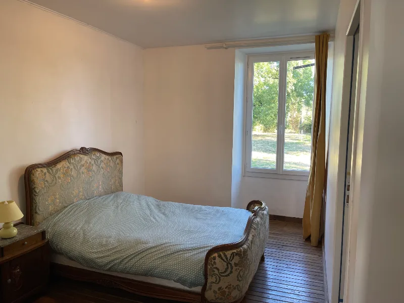 Chambre meublée à l'ancienne avec tête de lit sculptée et vue sur le parc