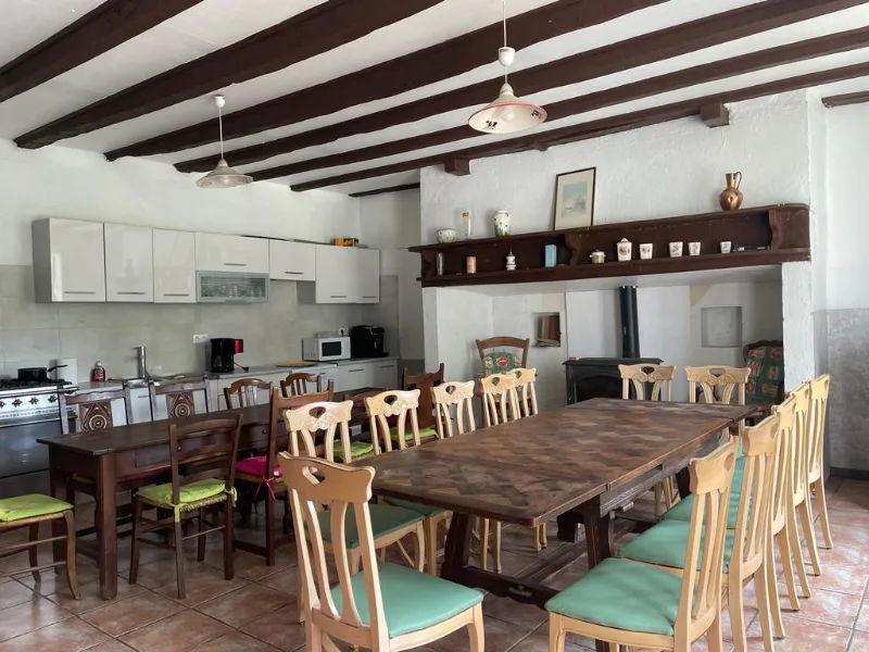Grande cuisine-salle à manger avec longue table en bois massif pour les repas de groupe