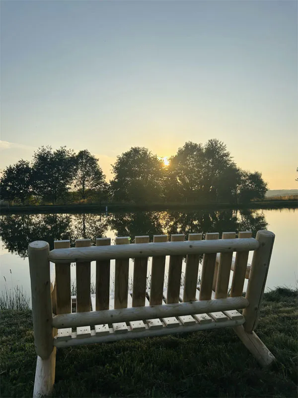 Banc en bois face à l'étang du domaine au coucher du soleil, coin calme du parc