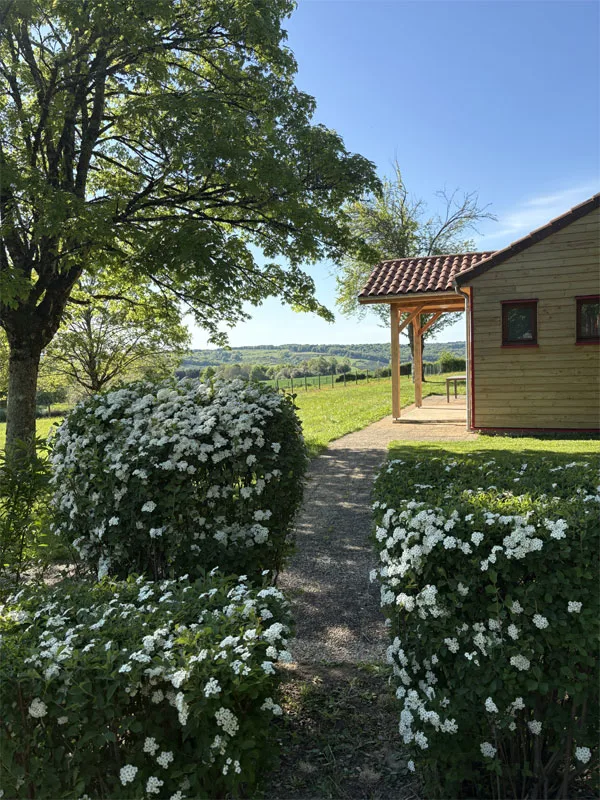 Chalet en bois du Village de Gîtes La Perdicie entouré de verdure dans le parc de trois hectares
