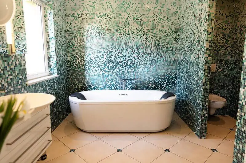 Salle de bain habillée de mosaïque verte avec baignoire îlot blanche