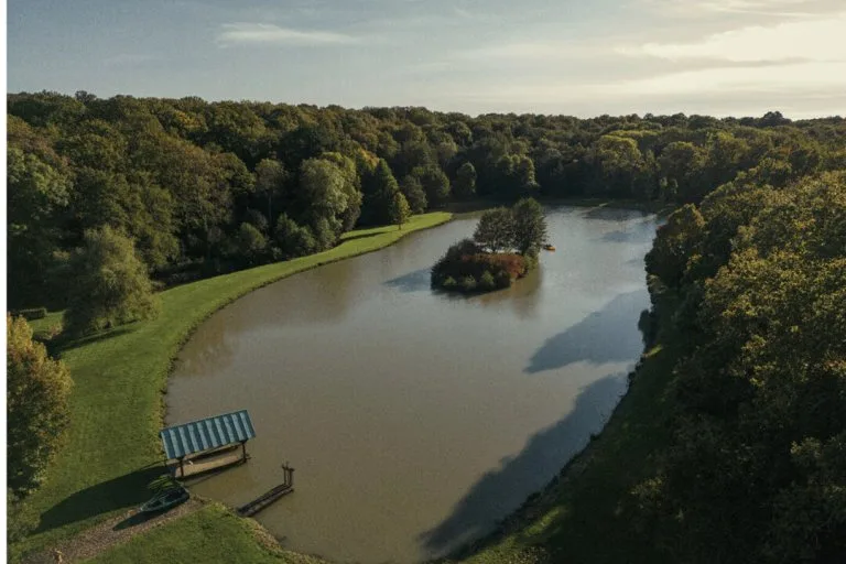 Vue aérienne du parc et de l'étang serpentant entre les arbres du domaine